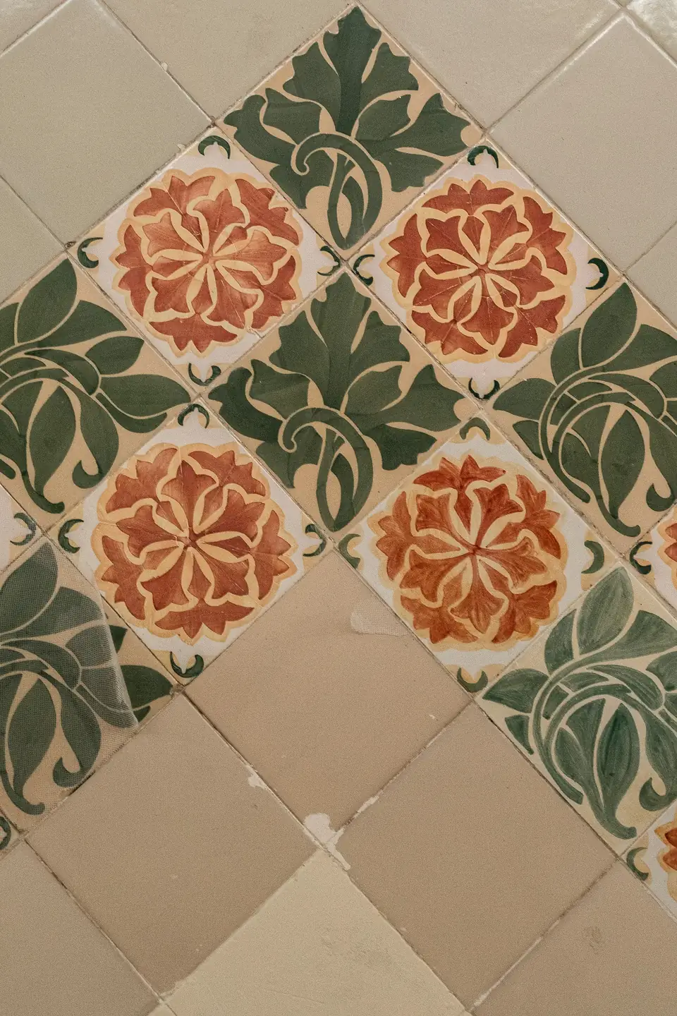 Carreaux à fleurs rouges et feuillages verts posés en diagonale, raccord avec des carreaux unis