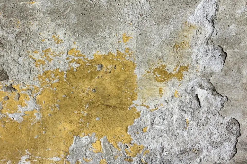 Peinture jaune qui s’écaille sur un enduit gris abîmé
