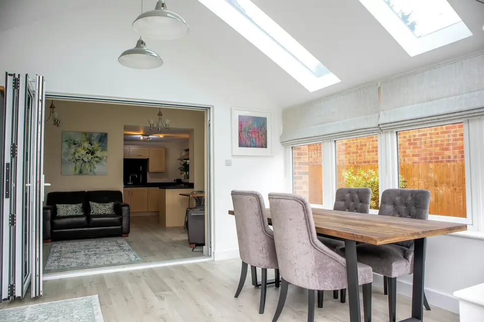 Pièce à vivre agrandie : plafond en pente percé de fenêtres de toit, table de repas