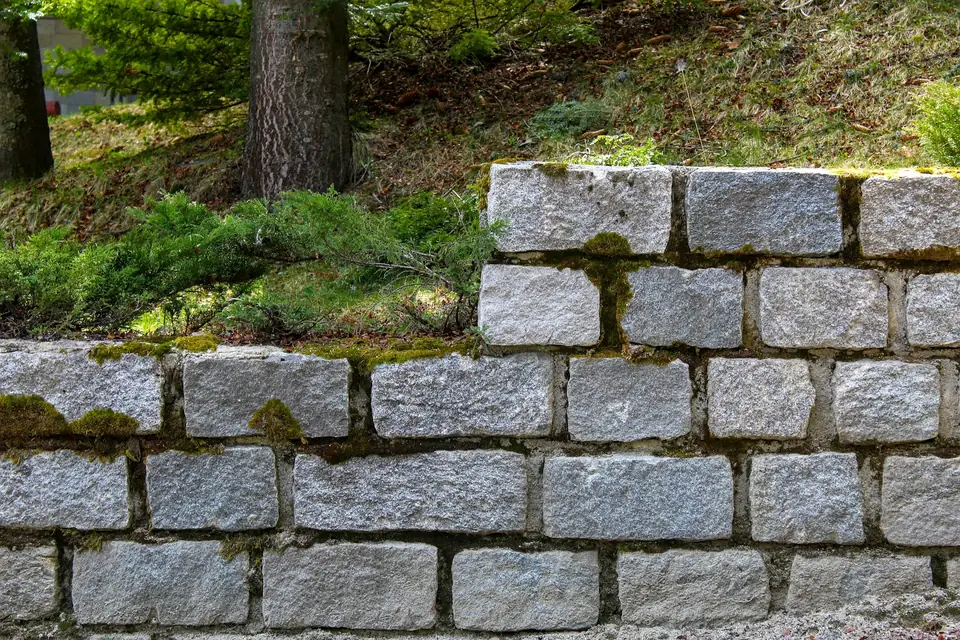 Muret de soutènement en blocs gris au bord d’une pelouse