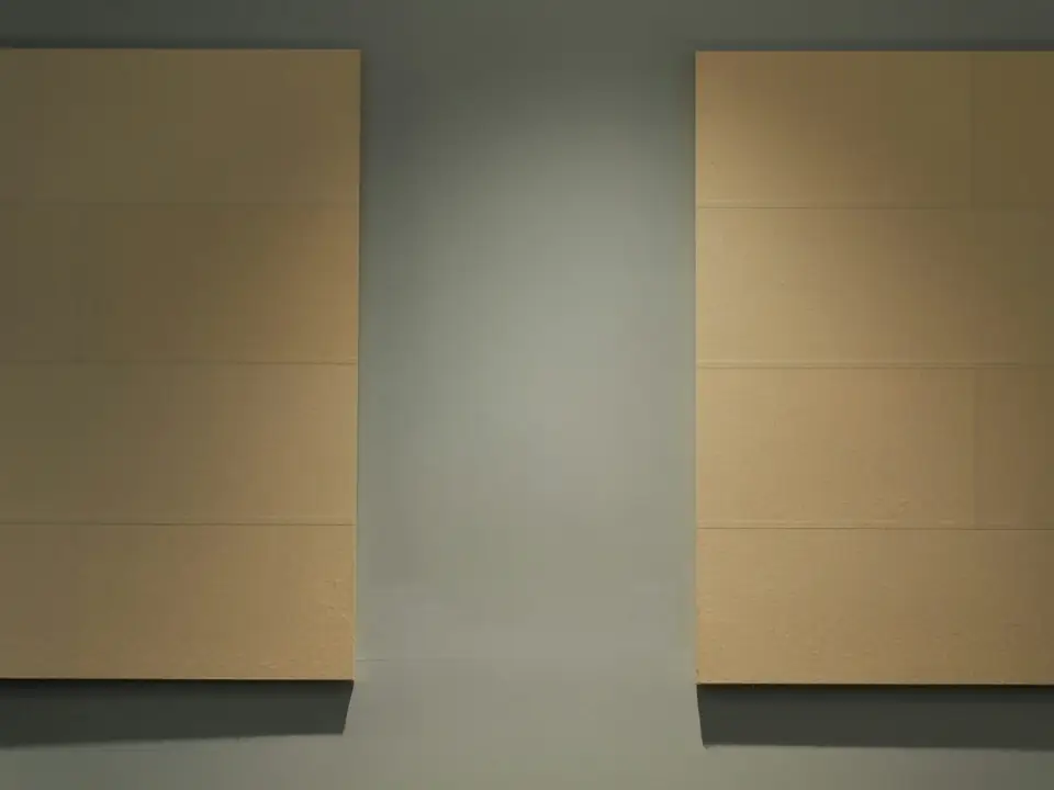 Deux panneaux acoustiques couleur sable fixés sur un mur gris