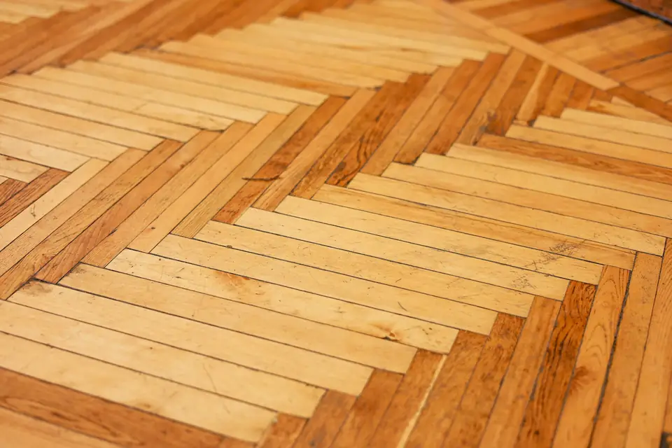 Gros plan sur un parquet à motif, lames étroites et fil du bois bien visible