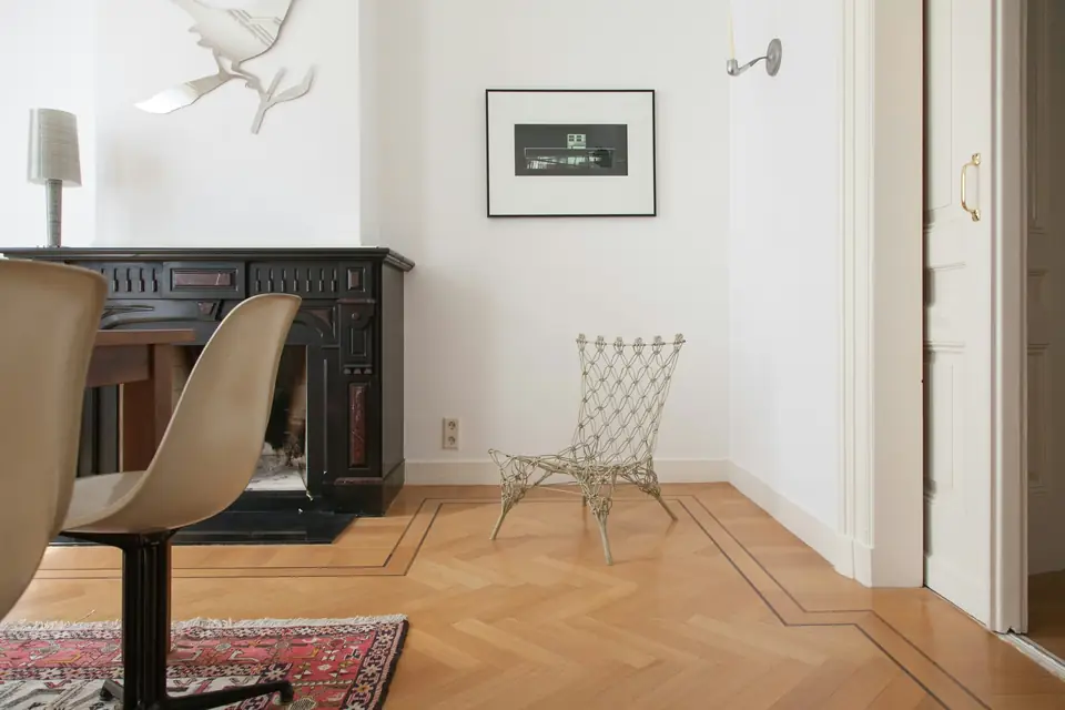 Pièce claire au parquet à motif encadré d’une frise, chaise et tapis ancien