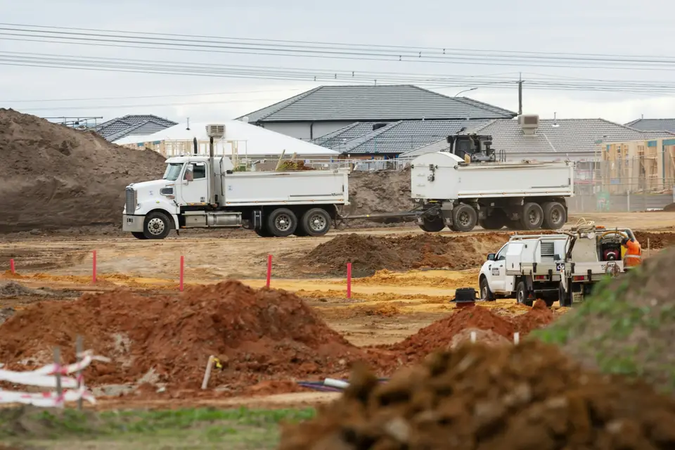 Camions-benne sur des parcelles en terrassement, plateformes prêtes pour les maisons